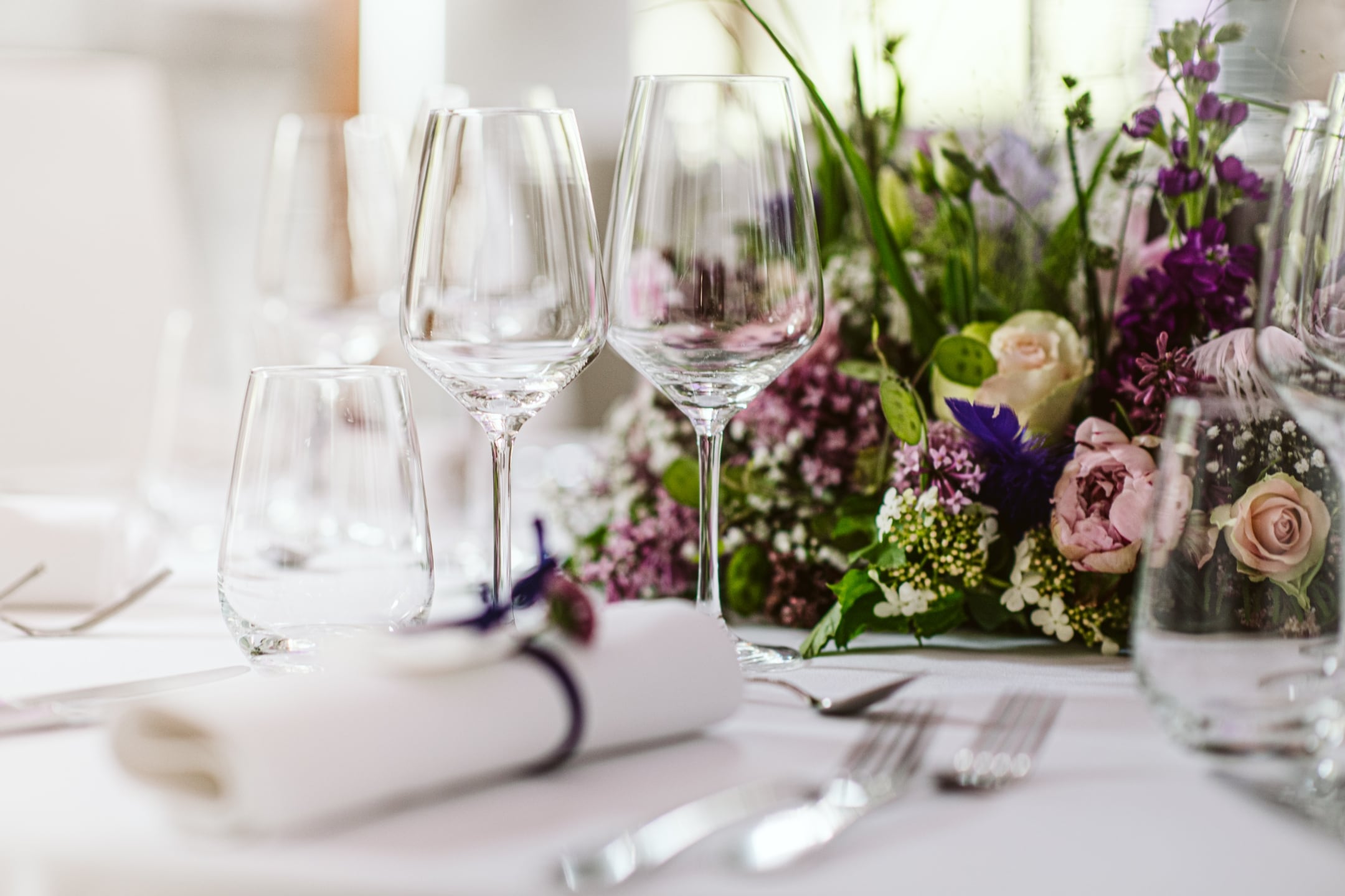 Tisch mit weißen Tischdecken, Weingläsern und einem schönen Bouquet
